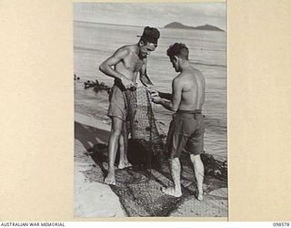 SACHEN BAY, SALAMAUA AREA, NEW GUINEA. 1945-10-29. PRIVATE K. WITCHARD (1) AND PRIVATE A.C. PRICE (2), MEMBERS OF 2 MARINE FOOD SUPPLY PLATOON, REPAIRING THEIR NETS WHICH HAVE BEEN TORN ON SNAGS. ..