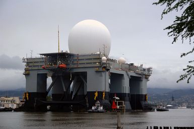 The Sea Based X-Band Radar (SBX) is assisted by commercial tugboats, as it departs Pearl Harbor, Hawaii (HI) after a three-month port visit. The SBX arrived to undergo minor modifications, post-transit maintenance and routine inspections. The on-board propulsion system allows SBX to transit to its homeport in Adak, Alaska in the Aleutian Islands. The SBX will provide the nation with highly advanced ballistic-missile detection