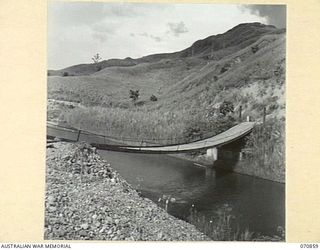 WAU - LAE ROAD, NEW GUINEA, 1944-02-20. A SUSPENSION BRIDGE NEAR THE WATUT RIVER JUNCTION ABOUT 25 MILES FROM WAU. THE ROADWAY AT THIS POINT IS BUILT ON DREDGE CASTINGS