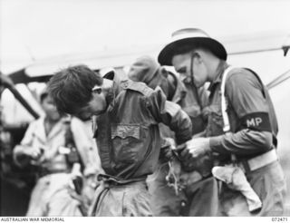 DUMPU, NEW GUINEA. 1944-04-19. A JAPANESE PRISONER OF WAR HAVING HIS HANS UNTIED BY A MILITARY POLICEMAN AFTER ARRIVING BY AIRCRAFT FOR INTERROGATION BY INTELLIGENCE OFFICERS AT HEADQUARTERS 11TH ..