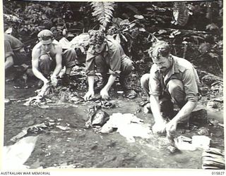 NEW GUINEA. ADVANCE ON LAE. WASHING THEIR CLOTHES IN A CREEK ON THE WAY TO LAE ARE - LEFT TO RIGHT GNR. R. LENEUF OF ABBOTSFORD, VIC. GNR. T. CRACKWELL OF QUEENSCLIFF, VIC., GNR. H. HIATT OF ..