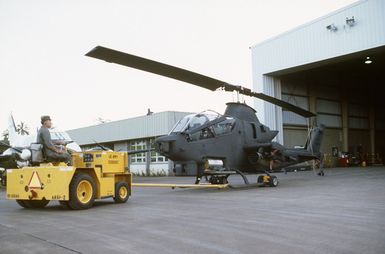 A Hawaii Army National Guard AH-1 Cobra helicopter is towed out of a hangar during Exercise OPPORTUNE JOURNEY 85-3