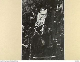 SHAGGY RIDGE, NEW GUINEA. 1943-12-27. NATIVE STRETCHER BEARERS SETTING OFF FOR THE 2/16TH AUSTRALIAN INFANTRY BATTALION, 21ST AUSTRALIAN INFANTRY BRIGADE REGIMENTAL AID POST ON A LONG WINDING TRACK ..