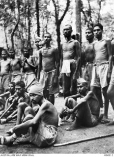 KUMUIA YAMA, RABAUL AREA, NEW BRITAIN. 1945-09-17. A GROUP OF INDIAN TROOPS AT THE INDIAN PRISONER OF WAR CAMP. THEY REFLECT THE ILL TREATMENT METED OUT BY THE JAPANESE. SOME ARE TOO WEAK TO STAND. ..