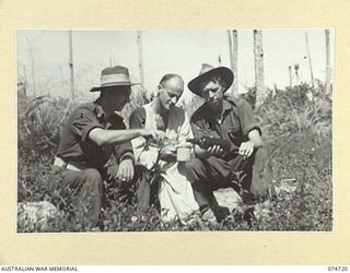 ALEXISHAFEN, NEW GUINEA. 1944-07-16. A PATIENT OF THE 2/15TH FIELD AMBULANCE HAVING A DRINK WITH HIS FRIENDS IN THE HOSPITAL GROUNDS. IDENTIFIED PERSONNEL:- VX68698 DRIVER SIDNEY THOMAS CORRIE (1); ..