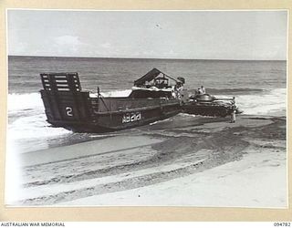 TOROKINA AREA, BOUGAINVILLE, 1945-08-06. AN M24 GENERAL CHAFFEE LIGHT TANK TRIES TO PUSH THE STERN OF AUSTRALIAN LANDING CRAFT 40 INTO DEEPER WATER. THE BEACHED VESSEL BROUGHT THE TWO TANKS INTO ..