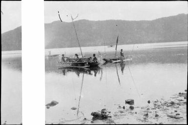 Group of people standing in and around two outrigger canoes with two boats in the background, Papua, ca. 1923 / Sarah Chinnery