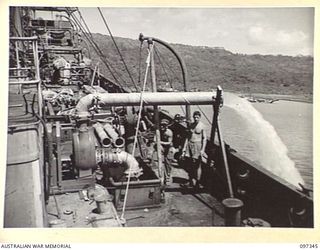 RABAUL, NEW BRITAIN. 1945-09-30. ONE OF THREE LARGE PUMPS OPERATED BY MEMBERS OF COMMONWEALTH MARINE SALVAGE BOARD AT WORK ON THE DECK OF JAPANESE TANKER NO. 5301. EACH PUMP DELIVERS SIX HUNDRED ..