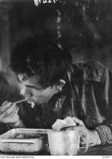 DUMPU, NEW GUINEA. 1944-04-19. USING HIS PERSONAL CHOPSTICKS A JAPANESE PRISONER OF WAR ENJOYS A MEAL AFTER BEING INTERROGATED BY INTELLIGENCE OFFICER AT HEADQUARTERS 11TH DIVISION