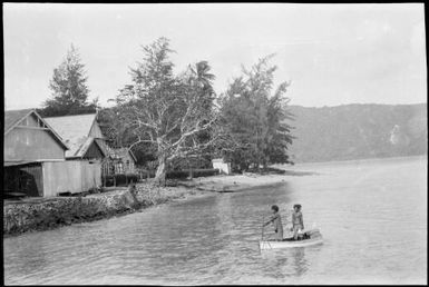 Two people in a boat with a European style building in the background, Samarai, Papua, ca. 1929, 2 / Sarah Chinnery