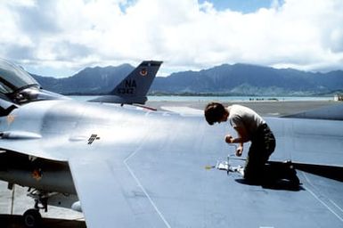 An airman unscrews an access panel of an F-16 Fighting Falcon aircraft wing for maintenance during exercise COPE ELITE '81. The airman is from the 428th Tactical Fighter Squadron, 474th Tactical Fighter Wing