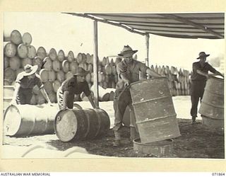 LAE, NEW GUINEA. 1944-03-30. MEMBERS OF THE 54TH BULK ISSUE PETROL AND OIL DEPOT PLATOON PROCESSING EMPTY DRUMS FOR SHIPMENT TO THE MAINLAND. THE DRUMS ARE DRAINED, THE DRAININGS SALVAGED, AND ..