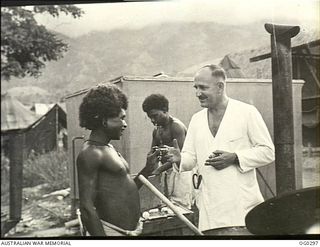 NEW GUINEA. C. 1943-09. SQUADRON LEADER D. R. MUNRO OF GLOUCESTER, NSW, MEDICAL OFFICER OF NO. 2 MEDICAL RECEIVING STATION (DETACHMENT), LOCATED AT A FORWARD RAAF HOSPITAL, REWARDS A NATIVE BOY ..