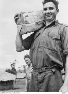 RAMU VALLEY, NEW GUINEA. 1943-12-22. QX32940 PRIVATE J. A. FORREST 2/31ST AUSTRALIAN INFANTRY BATTALION PROUDLY DISPLAYS HIS CHRISTMAS PARCEL FROM HOME SOON AFTER COLLECTING IT AT THE 7TH ..