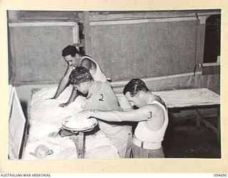 YALU, NEW GUINEA. 1945-08-03. SERGEANT DALEY (3), CUTTING AND SCALING DOUGH IN THE BAKING WING OF THE NEW GUINEA TRAINING SCHOOL. IDENTIFIED PERSONNEL ARE:- PRIVATE A.M.S. JONES (1); TROOPER G. ..