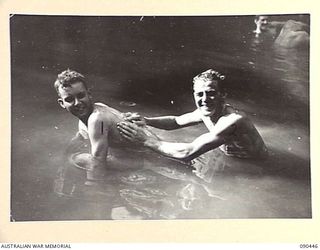 WONGINARA MISSION, NEW GUINEA. 1945-04-04. PRIVATE J.O. MCINTYRE (LATER KILLED IN ACTION) (1), HAS HIS BACK WASHED BY SERGEANT A.J. BENSLEY (2). THE MEN, MEMBERS OF THE 2/3 INFANTRY BATTALION, HAVE ..