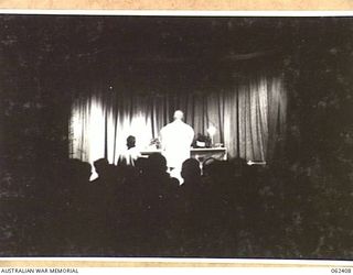 PORT MORESBY, PAPUA, NEW GUINEA. 1943-12-24. MIDNIGHT MASS CHRISTMAS EVE BEING CELEBRATED BY NX34952 CHAPLAIN F. H. GALLAGHER (1) WITH NX45303 PRIVATE J. A. SMITH, (2) SERVING AT THE ALTAR MORESBY ..