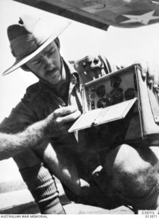 PAPUA. 1942-11-14. CAPT. R.W. LONIE OF QUEENSLAND DISPLAYS A PORTABLE WIRELESS SET CAPTURED FROM A JAPANESE PATROL. THESE SETS, USED BY JAPENESE PATROLS TO KEEP IN TOUCH WITH EACH OTHER WEIGH ONLY ..