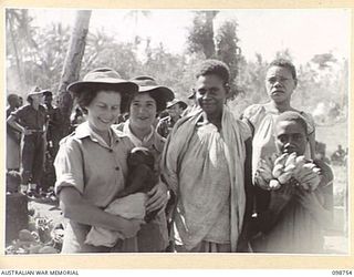 RABAUL, NEW BRITAIN. 1945-11-10. AUSTRALIAN ARMY MEDICAL WOMEN'S SERVICE PERSONNEL FROM 118 GENERAL HOSPITAL NURSING A NATIVE CHILD DURING THEIR VISIT TO THE NATIVE MARKET AT TALILI BAY IN 4 ..