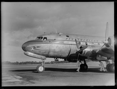 View of the PAA's Douglas DC 4 Clipper Polynesia CN 88956 passenger plane with unidentified ground crew at [Whenuapai Airfield, Auckland?]