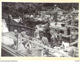 FAURO ISLAND, BOUGAINVILLE AREA. 1945-10-01. JAPANESE MEDICAL ORDERLIES CARRYING STRETCHER CASES ASHORE FROM A LANDING BARGE FOR MOVEMENT TO A JAPANESE HOSPITAL IN THE CONCENTRATION CAMP AREA. ..