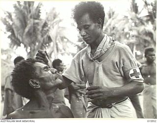 1943-10-08. NEW GUINEA. KAIAPIT. MAKY FROM PORT MORESBY, A TRAINED MEDICAL BOY ATTENDS TO AN OLD VILLAGE CHIEF. A WEEK PREVIOUSLY THE NATIVES HAD BEEN CONTROLLED BY THE JAPANESE. THEY WERE GIVEN NO ..