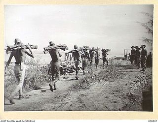 NAMATANAI, NEW IRELAND. 1945-10-29. A LINE OF JAPANESE CARRYING RIFLES TO THE JETTY TO BE DUMPED IN THE SEA. TROOPS OF 11 INFANTRY BATTALION, 13 INFANTRY BRIGADE, ARE SUPERVISING THE DUMPING OF ALL ..