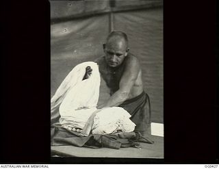 VIVIGANI, GOODENOUGH ISLAND, PAPUA. 1943-12-26. LEADING AIRCRAFTMAN H. MOSES OF NEWTON, NSW, AND NO. 30 (BEAUFIGHTER) SQUADRON RAAF, FOLDING A PARACHUTE FOR USE BY BEAUFIGHTER CREWS