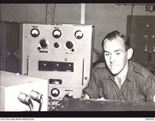 LAE, NEW GUINEA, 1945-12-21. WARRANT OFFICER 1 HENDERSON, TECHNICIAN, TESTING EQUIPMENT IN THE CONTROL ROOM OF THE AUSTRALIAN ARMY AMENITIES SERVICE RADIO STATION 9AB
