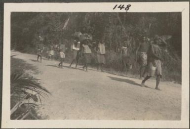 Group of people on their way to market, New Britain Island, Papua New Guinea, approximately 1916
