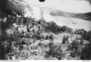 Rabaul, New Britain. 1943-11-02. Aerial photograph of shipping in the harbour and smoke rising from the town, during an air attack by seventy-five Mitchell aircraft covered by Lightnings of the ..
