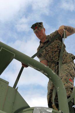 US Marine Corps (USMC) Lance Corporal (LCPL) Spangler, assigned to Combat Service Support Group 3 (CSSG-3), Marine Forces Pacific (MARFORPAC) uses a tie down strap to secure a Combat Camera and Printing (CC&P) air conditioning unit onto a transport truck at Camp H.M. Smith, Hawaii (HI), as the Unit prepares for deployment to Iraq, in support of Operation IRAQI FREEDOM