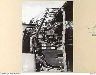 BOUGAINVILLE. 1945-08-30. PERSONNEL OF 2/4 ARMOURED REGIMENT WORKSHOP, LOWERING AN ENGINE INTO THE HULL OF A TANK AFTER REPAIRS. CRANES ARE USED TO REMOVE MOTORS TO FACILITATE REPAIR WORK