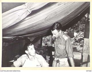 RABAUL, NEW BRITAIN. 1945-09-23. LIEUTENANT COLONEL F. COX, COMMANDING OFFICER 11 DIVISION SIGNALS, CONFERRING WITH HIS ADJUTANT CAPTAIN L.D. MEARES, THE COMMAND GROUP, 11 DIVISION SIGNALS