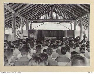 LAE, NEW GUINEA, 1945-05-09. CHAPLAIN E.M. WATTS READING A PASSAGE FROM THE SCRIPTURE TO MEMBERS OF HIS CONGREGATION AT 112 CONVALESCENT DEPOT DURING A THANKSGIVING SERVICE TO MARK THE END OF ..