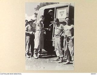 LAE AREA, NEW GUINEA. 1944-12-20. PRIVATE W H CRANE, (3), SERVING TEA TO 4 ADVANCED ORDNANCE DEPOT TROOPS FROM A YMCA AUSTRALIAN COMFORTS FUND TRUCK. CORPORAL W R WATSON, THE DRIVER, (4) STANDS ..