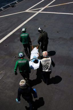 U.S. Navy Military Sealift Command Mercy Class Hospital Ship USNS MERCY (T-AH 19) flight deck personnel carry a litter borne patient to a waiting Helicopter Sea Combat Squadron 25 (HSC-25, ΦIsland Knightsτ) MH-60S Knight Hawk (Sierra) helicopter for a return trip back to the city of Dili, East Timor, Indonesia, on Aug. 29, 2006. HSC-25 is from Guam and has helped transport U.S. medical personnel and Indonesian patients to and from the sip, while the MERCY is in the fourth month of a five-month humanitarian and civic assistance deployment to Southeast Asia. (U.S. Navy photo by Mass Communication SPECIALIST SEAMAN Mike Leporati) (RELEASED)