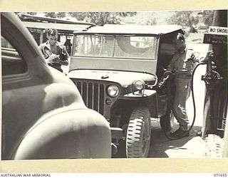 PORT MORESBY, PAPUA, NEW GUINEA. 1944-03-29. NX155436 DRIVER FERRIS (1), WITH VX100531 DRIVER BUCHNER (2), SERVING A JEEP FROM A PETROL DUMP AT TRANSPORT SECTION, HEADQUARTERS NEW GUINEA FORCE