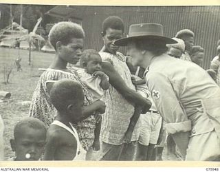 LAE, NEW GUINEA. 1945-03-27. LADY WAKEHURST, TALKS TO A NATIVE CHILD IN THE ARMS OF ITS MOTHER DURING A VISIT TO THE FAMILIES OF MEMBERS OF THE ROYAL PAPUAN CONSTABLULARY