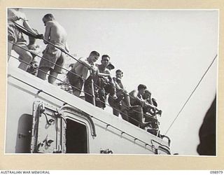 WEWAK HARBOUR, NEW GUINEA. 1945-11-25. TROOPS OF 6 DIVISION, TAKING A LAST LOOK AT WEWAK FROM B DECK, HMAS SHROPSHIRE. THE TROOPS ARE RETURNING TO AUSTRALIA FOR DISCHARGE