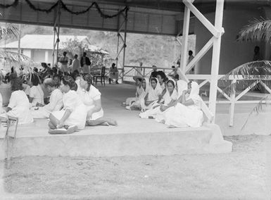 [Young pacific island girls in uniform sitting on the edge of an open air pavilion]