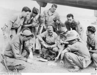 NEW GUINEA, 1942-08-10. A CLOSE-UP OF AMERICAN AND AUSTRALIAN BOMBER CREWS GROUPED AROUND THEIR TARGET MAPS, AS THEY GET INSTRUCTIONS BEFORE SETTING OUT ON A RAID OVER JAP BASES