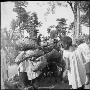 Heavily laden people, Boong, native market, Rabaul, New Guinea, ca. 1936 / Sarah Chinnery