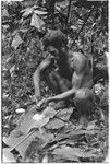 Ubuni scraping coconut meat from shell for ritual pudding