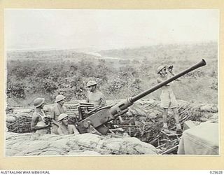 PORT MORESBY, PAPUA. 1942-07. AUSTRALIAN ANTI-AIRCRAFT GUNNERS IN NEW GUINEA KEEP A SHARP LOOK-OUT FOR JAPANESE RAIDERS DURING AN "ALERT". NOTE SHELLS IN POSITION ON GUN, WITH MORE READY IN MAN'S ..