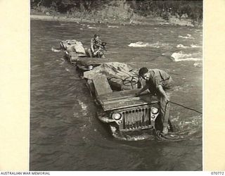 WAMPIT, NEW GUINEA, 1944-03-02. NX81806 SERGEANT D. TODD, TRANSPORT SERGEANT OF THE 9TH FIELD COMPANY, ROYAL AUSTRALIAN ENGINEERS (1) LENGTHENS A TOWLINE ON A JEEP CROSSING THE RIVER AT WAMPIT. THE ..