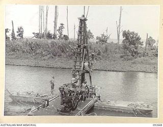 BOUGAINVILLE. 1945-05-30. SAPPERS OF 11 FIELD COMPANY ROYAL AUSTRALIAN ENGINEERS, USING A PILE DRIVER ERECTED ON PONTOONS TO DRIVE PILES TO ANCHOR THE NEWLY CONSTRUCTED SAVIGE BRIDGE OVER THE JABA ..