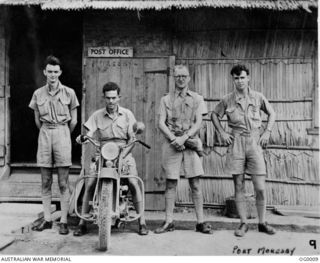 PORT MORESBY. FOUR RAAF AIRMEN, ONE SEATED ON HIS MOTOR BIKE, OUTSIDE THE POST OFFICE