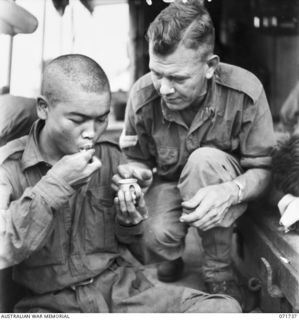 WASU, PAPUA, 1944-03-25. VX63224 CORPORAL E. R. SMITH (RIGHT), 2/5TH FIELD AMBULANCE GIVING ASSISTANCE TO A JAPANESE PRISONER OF WAR