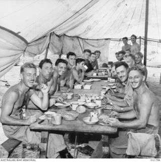 MOMOTE, LOS NEGROS ISLAND, ADMIRALTY ISLANDS. C. 1944-04. INFORMAL GROUP PORTRAIT OF MEMBERS OF NO. 76 (KITTYHAWK) SQUADRON RAAF EATING A MEAL IN THE MESS TENT